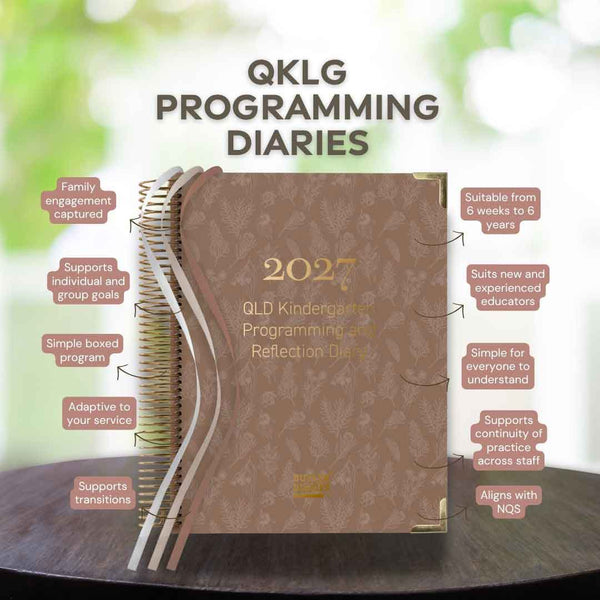 2027 QLKG Programming Diaries on a wooden surface with greenery in the background