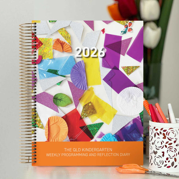 The QLD Kindy Weekly Programming and Reflection Diary for QKLG with the Child Artist Cover on a QLD Kindergarten Teacher's desk