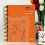 Orange '2026 Educational Leader Diary' with decorative cover and stationery items on a desk.
