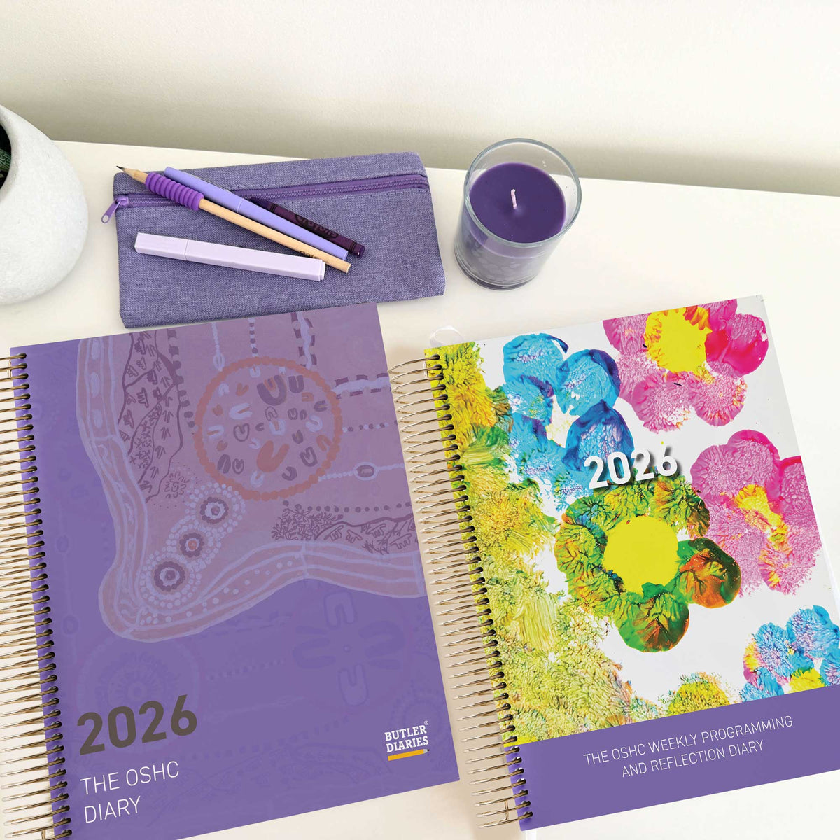 OSHC Diary with Journey of Learning First Nations Artwork Cover and OSHC Weekly Programming and Reflection Diary with Child Artwork Cover sitting on an OSHC Educator's desk