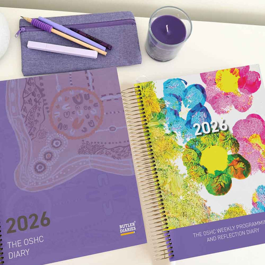 Two diaries, one purple and one with a colorful design, on a white surface with a candle.