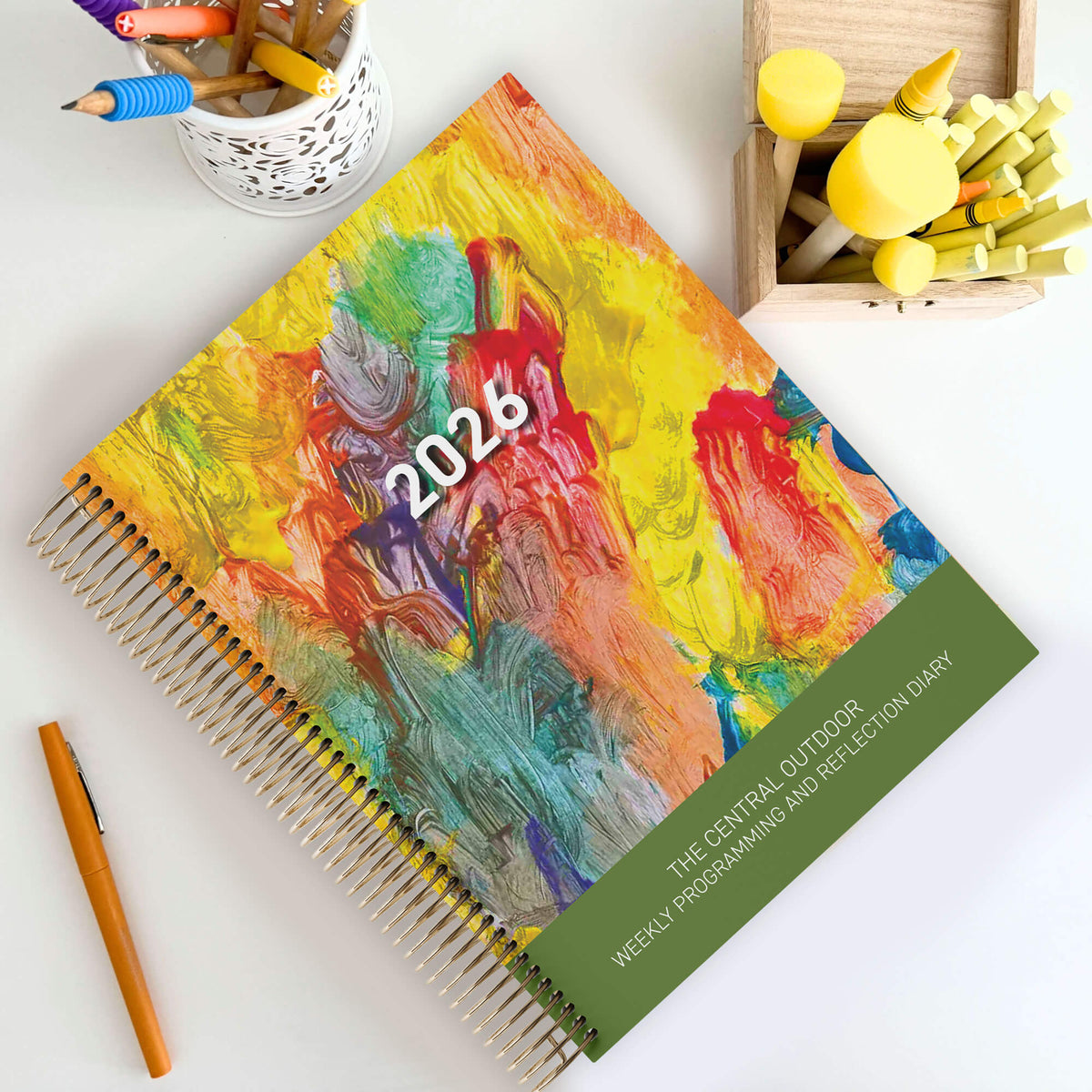 Central Outdoor Weekly Programming and Reflection Diary for EYLF with Child Artwork Cover sitting on an outdoor ECEC table