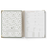 Open spiral-bound book with floral pattern on one page and text on the other, on a white background.