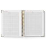 Open spiral-bound planner with grid pages on a white background
