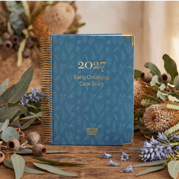 Blue spiral-bound diary titled '2027 Early Childhood Cook Diary' with floral decorations on a wooden surface.
