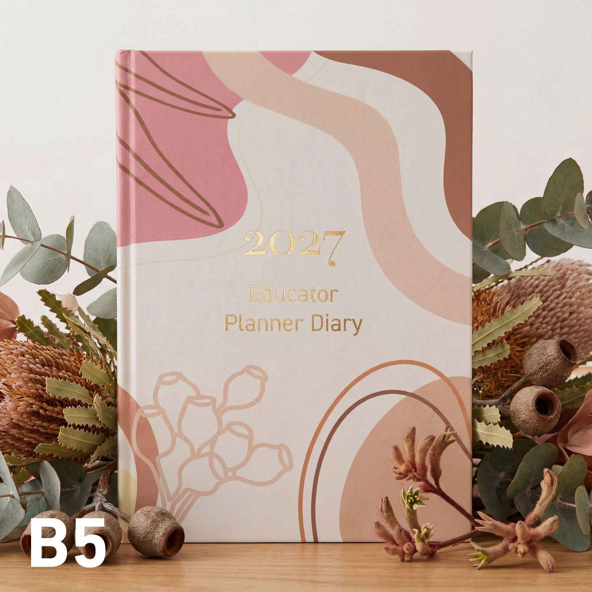 2027 Educator Planner Diary with floral design on a wooden surface with eucalyptus leaves.