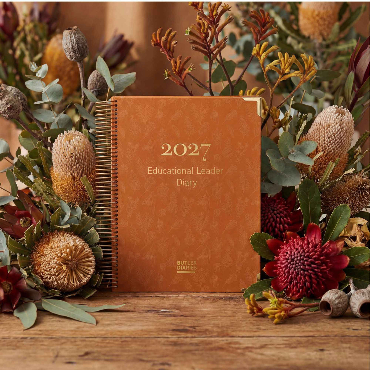 2027 diary with floral arrangement on a wooden surface