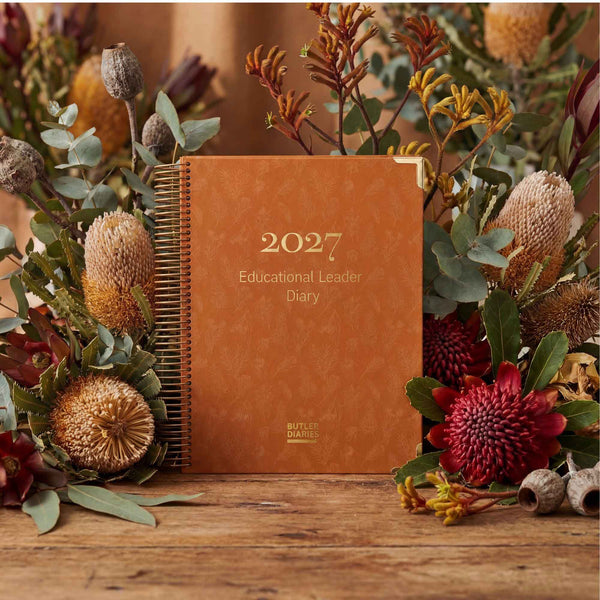 2027 diary with floral arrangement on a wooden surface