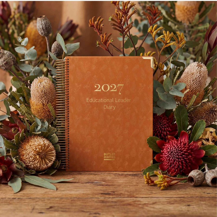 2027 diary with floral arrangement on a wooden surface