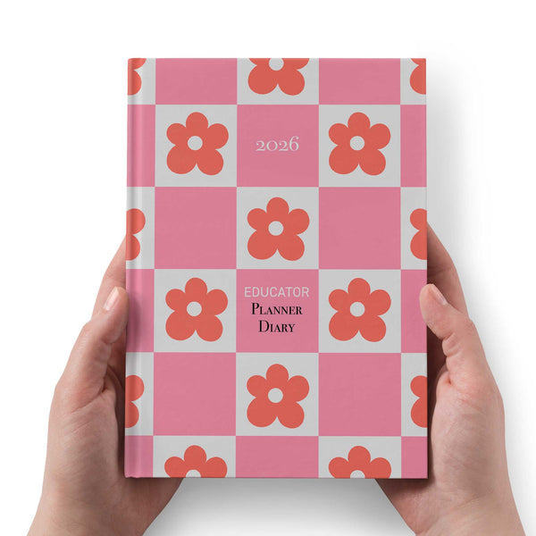 Planner diary with pink and red flower pattern held by hands on a white background