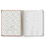 Open spiral-bound planner with floral pattern on left page and text on right page.
