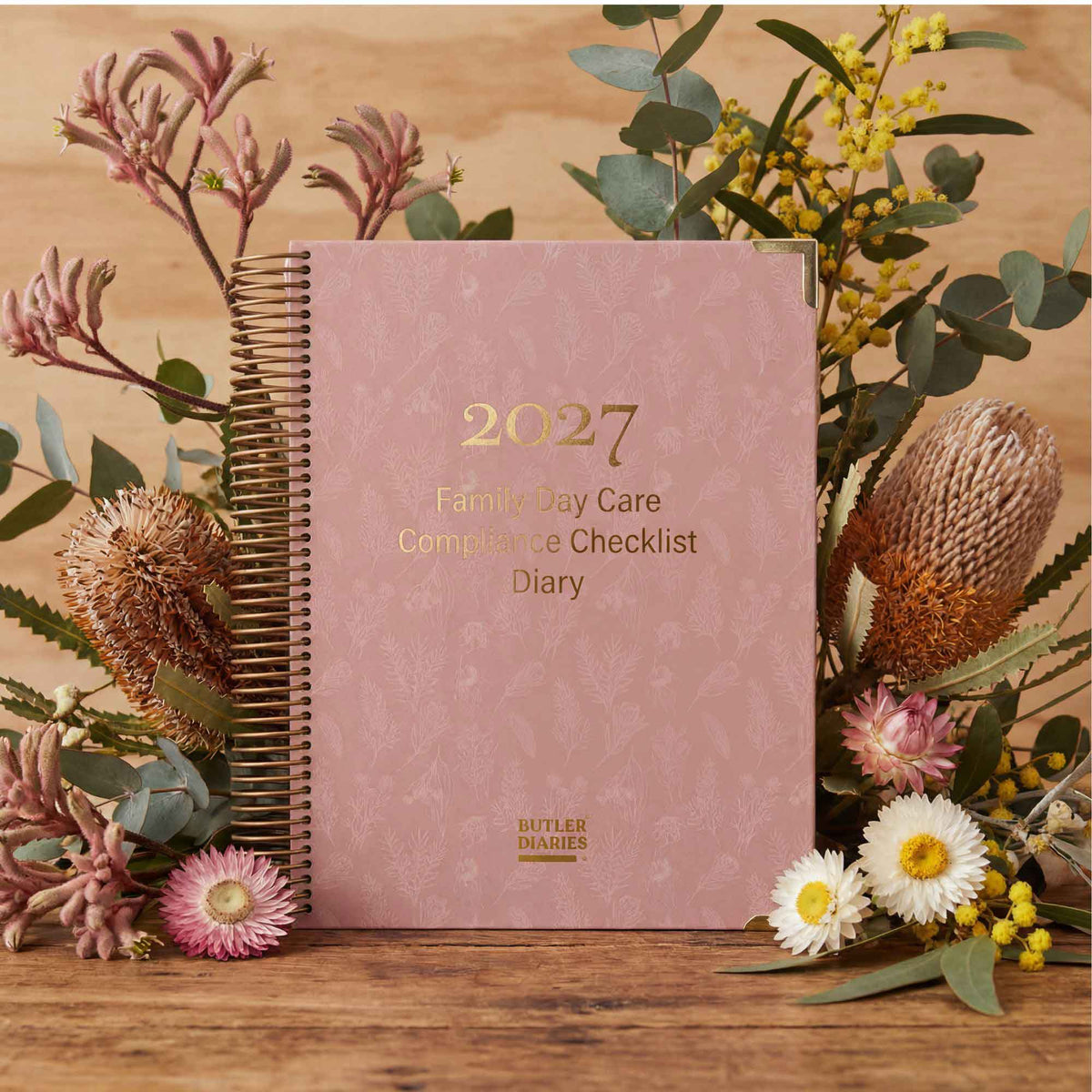 2027 Family Day Care Compliance Checklist Diary on a wooden surface with flowers