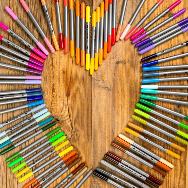Colorful markers arranged in a circular pattern on a wooden surface