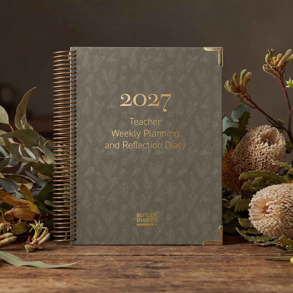 2027 Teacher Weekly Planning and Reflection Diary on a wooden surface with plants.