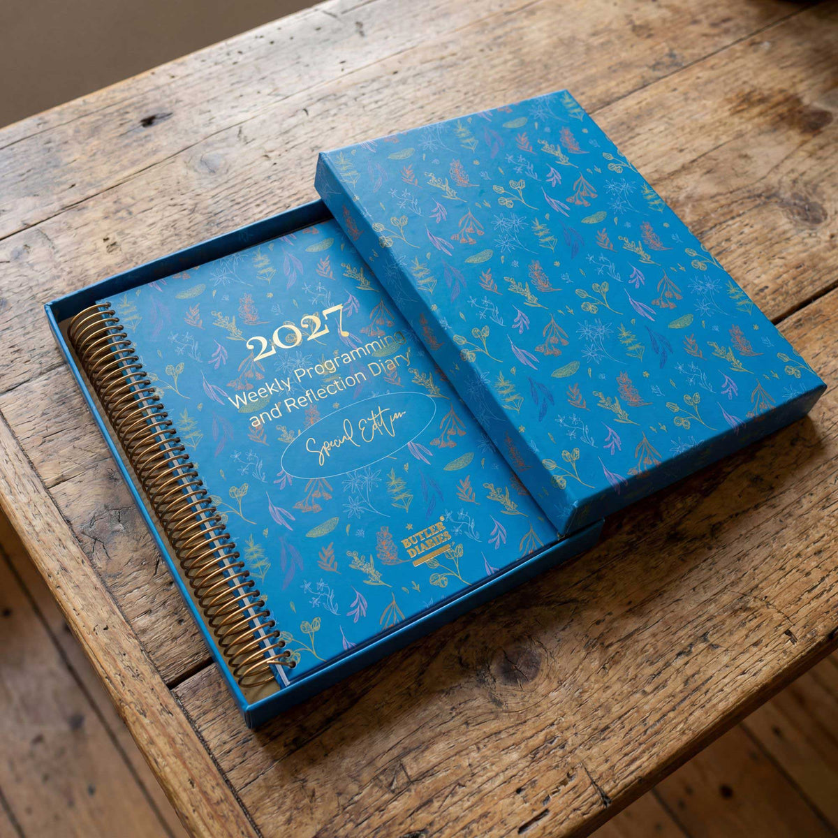 Blue weekly program diary in a gift box with 2027 on a wooden surface